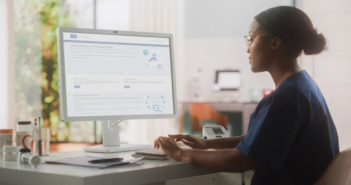 Female medical health care professional working on a desktop computer in a hospital office.