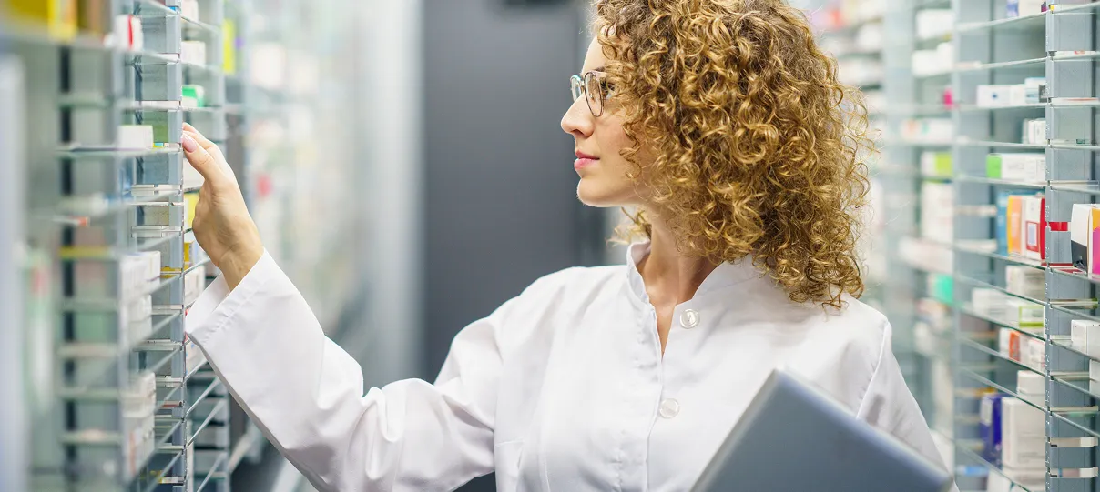 Female scientist or technician with curly hair holding a tablet and examining equipment or samples in a laboratory or data storage facility.