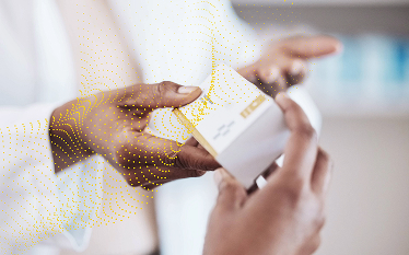 Close-up of a pharmacist handing a box of medication to a customer in a pharmacy.