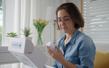 Person examining a pill bottle from a delivered package, highlighting concerns about illegal medicines