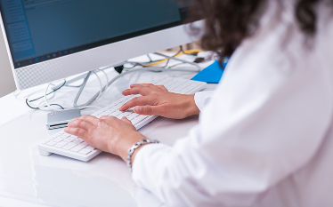Hands typing on a keyboard at a computer, illustrating regulatory work on medicine lifecycle management