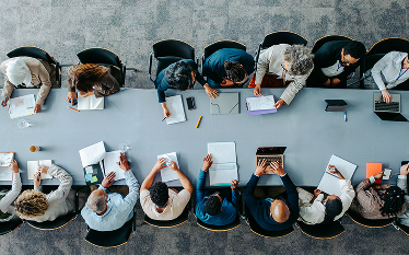 Overhead view of people seated around a conference table reviewing documents