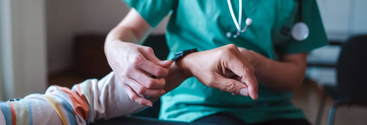 A doctor putting a measuring device on a patients wrist