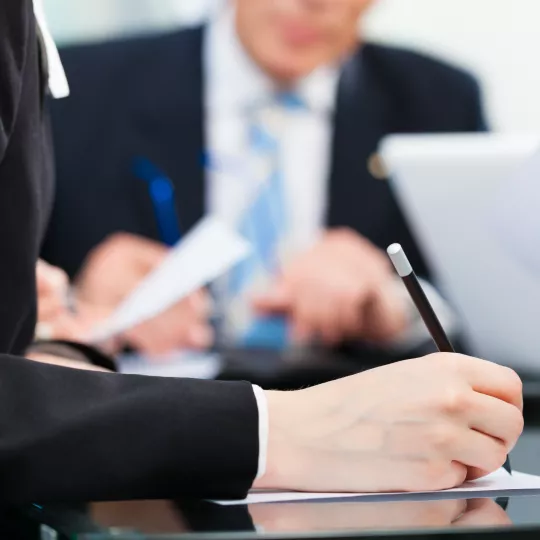 People sitting at desks, making notes and checking documents