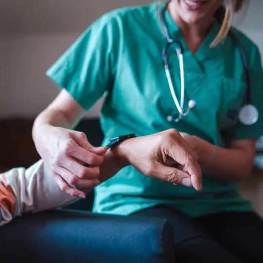 A nurse in green scrubs putting a clock on a patient