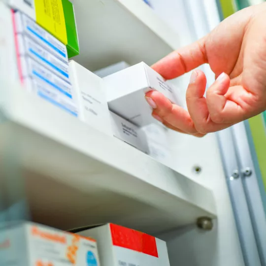 hand picking a medicine from the shelf