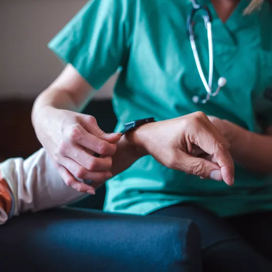 A doctor putting a measuring device on a patients wrist