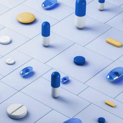 Pills of different shapes, sizes and colours displayed on a flat surface 